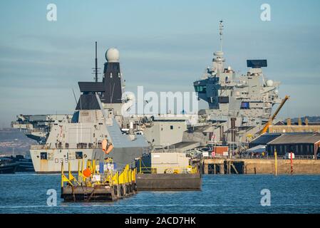 La Royal Navy Type 45 destroyer HMS Dragon (D35) arrivant à Portsmouth, Royaume-Uni le 2 décembre 2019 après participation à l'Westlant19 le déploiement. Le navire est vu étant déplacé à c'est à quai à l'arrière de la nouvelle classe Queen Elizabeth porte-avions HMS Prince de Galles. Banque D'Images