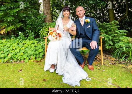 Mariés et mariés posent pour leurs photos après la cérémonie dans les jardins de l'hôtel Manor, B & B à Cheadle, Stoke on Trent, Staffordshire, jour du mariage Banque D'Images