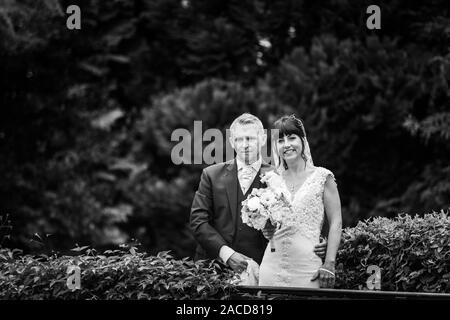 Mariés et mariés posent pour leurs photos après la cérémonie dans les jardins de l'hôtel Manor, B & B à Cheadle, Stoke on Trent, Staffordshire, jour du mariage Banque D'Images