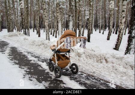 Snowy poussette de bébé en hiver forêt. les traces de pneus sur la neige. Infant baby dormir dans le landau sur l'air frais Banque D'Images