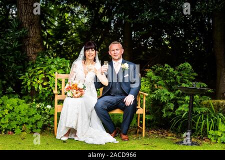 Mariée et mariée tenant du champagne après s'être mariée dans les jardins de l'hôtel Manor, B & B à Cheadle, Stoke on Trent, Staffordshire, jour du mariage Banque D'Images