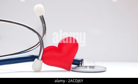 Concept de soins de santé : un coeur en tissu rouge à l'intérieur d'un stéthoscope sur tableau blanc Banque D'Images