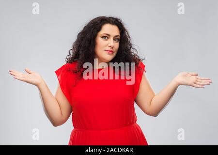 Femme en robe rouge en haussant sur fond gris Banque D'Images