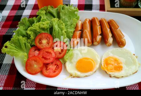 De la plaque d'œufs au plat avec des saucisses frites et salade fraîche pour le petit déjeuner Banque D'Images