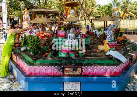 Une jeune femme verse de l'eau sur une statue bouddhiste à l'Meilamu Paya, Yangon, Myanmar. Banque D'Images