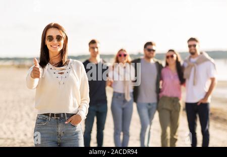 Femme avec des amis sur beach showing Thumbs up Banque D'Images