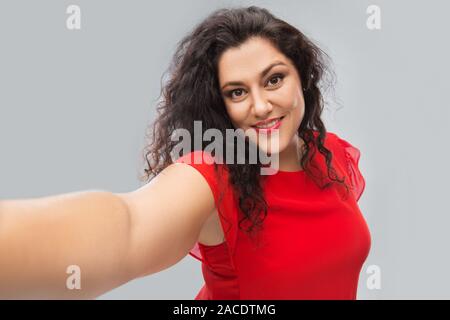 Happy woman in red dress selfies en tenant Banque D'Images