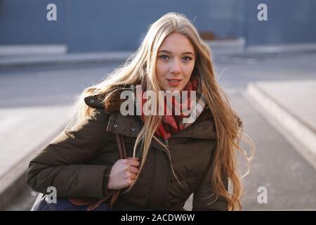 Street style franc portrait of teenage girl waiting at bus stop lors d'une journée ensoleillée en hiver Banque D'Images