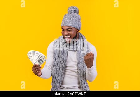 Heureux guy en hiver hat win lottery, regardant l'argent Banque D'Images