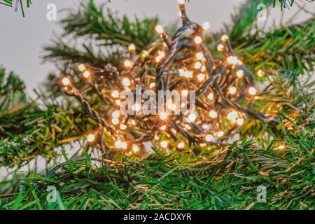 Arbre de Noël à l'intérieur effet bokeh fairy lights ballon éclairant. Une série de fêtes chaîne basse tension Voyants sur un câble vert foncé avec effet de lumière Banque D'Images