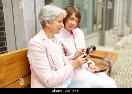 Happy senior femmes avec les smartphones en ville Banque D'Images