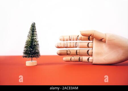 Noël arbre artificiel sur un support en bois et une main en bois Banque D'Images