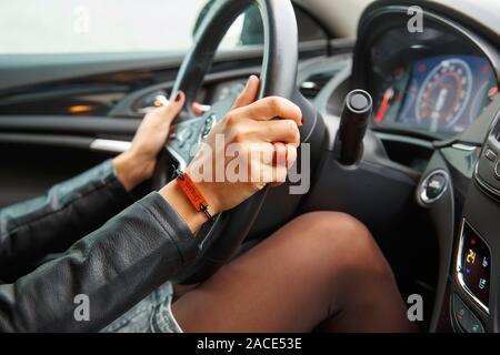 Concept de prise de vue : girl s mains sur le volant d'une voiture, un bracelet avec l'inscription dream sur sa main. Banque D'Images