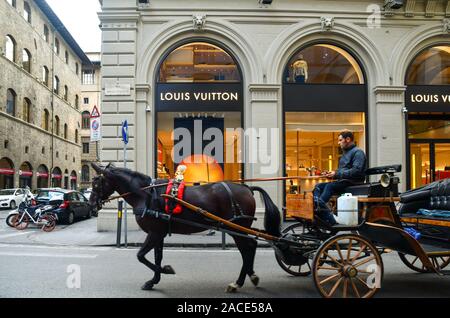 Balade en calèche en passant en face de la boutique Louis Vuitton, célèbre maison de haute couture, dans le centre historique de Florence, Toscane, Italie Banque D'Images