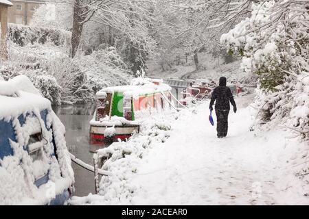 Femme marche prendre soin d'un traîneau en plastique dans l'accumulation de neige sur le chemin de halage Kennet et Avon à Bath, Angleterre, Royaume-Uni. Banque D'Images