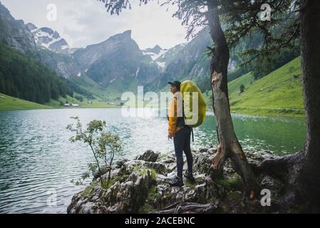 Femme portant un sac à dos jaune près du lac Seealpsee dans les Alpes d'Appenzell, en Suisse Banque D'Images