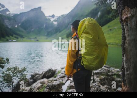 Femme portant un sac à dos jaune près du lac Seealpsee dans les Alpes d'Appenzell, en Suisse Banque D'Images