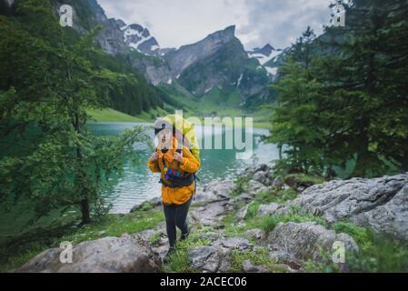 Femme portant des randonnées jaunes au bord du lac Seealpsee dans les Alpes d'Appenzell, en Suisse Banque D'Images