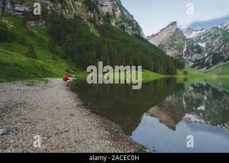 Femme en train de croupir au bord du lac Seealpsee dans les Alpes d'Appenzell, en Suisse Banque D'Images