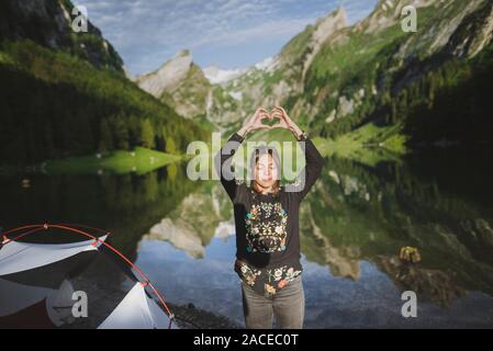 Femme faisant le coeur signe main par le lac Seealpsee dans les Alpes d'Appenzell, Suisse Banque D'Images