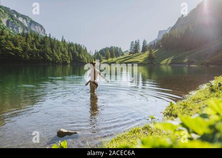 Femme nageant dans le lac Seealpsee, dans les Alpes d'Appenzell, en Suisse Banque D'Images
