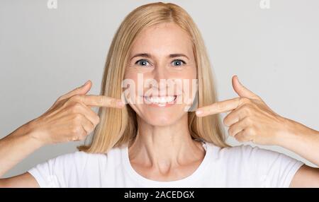Une dentition solide. Woman pointing sur son sourire parfait Banque D'Images