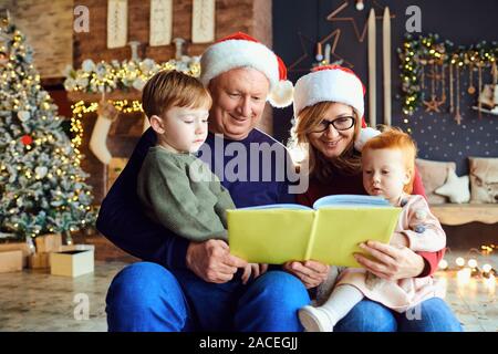 Les grands-parents lire un livre aux enfants à Noël Banque D'Images