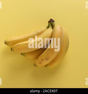 Les bananes sucrées sur fond jaune pastel punchy, vue du dessus Banque D'Images