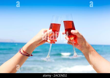 Mains de couple enjoying verres de champagne on tropical beach à sunny summer day Banque D'Images