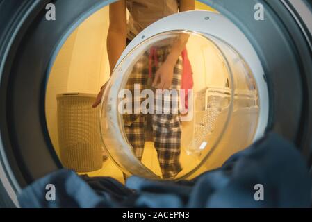 Femme ouvre la porte d'un lave-linge. Vue depuis un tambour de lave-glace. Concept de blanchisserie. Banque D'Images