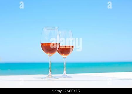 Deux verres de vin rose contre l'eau bleue et de la mer en été 24 Banque D'Images