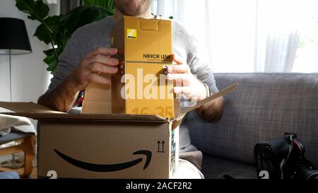 Paris, France - Circa 2019 : curieux homme unboxing déballage Amazon boîte en carton contenant l'e-commerce en ligne internet passé commande pour un Nikon 16-35 VR Banque D'Images