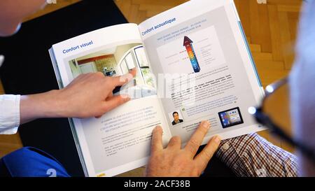 Paris, France - Circa 2019 : part à la recherche au marketing brochure catalogue divers type de fenêtres pour la nouvelle maison - young female manager d'expliquer au sujet de l'efficacité énergétique des fenêtres Banque D'Images
