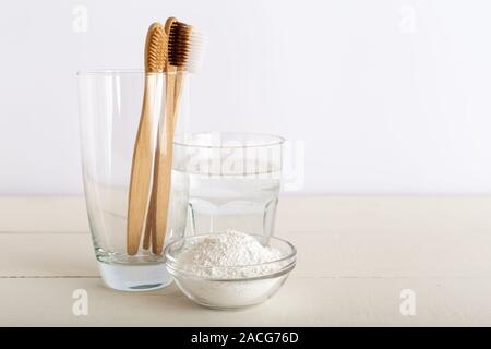 Brosses à dents en bambou, verre d'eau, le dentifrice dentifrice en poudre sur fond blanc. Brosse à dents naturelles de bambou biodégradable. Eco Friendly, zéro déchets Banque D'Images