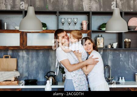 Happy friendly notion de famille. Maman, papa et petit fils hug dans leur cuisine à la maison Banque D'Images