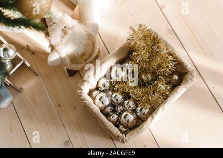 Panier avec des boules de Noël et les jouets sous l'arbre de Noël. La préparation pour décorer l'arbre de Noël. L'argent et boules d'or, les guirlandes avec fort sur un Banque D'Images