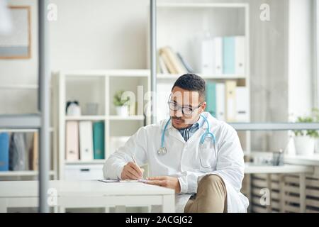 Portrait d'un médecin afro-américain dans les documents de dépôt alors qu'il était assis au bureau en clinique, copy space Banque D'Images