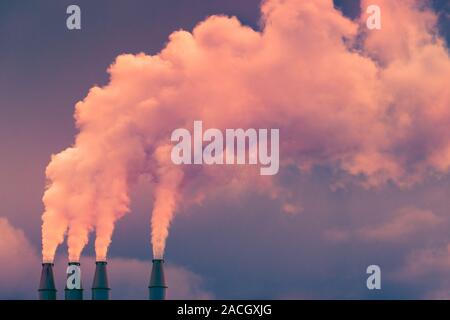 La fumée et la vapeur s'élevant dans l'air à partir de piles de la centrale ; les nuages sombres de l'arrière-plan ; concept pour la pollution de l'environnement et le changement climatique Banque D'Images