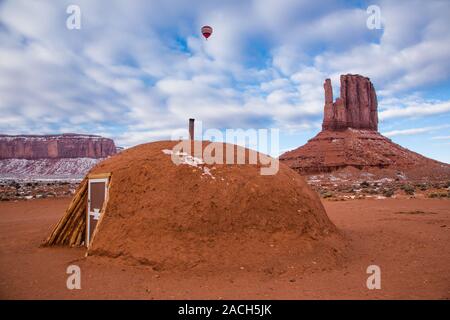 Une montgolfière survolant un hogan Navajo traditionnel et de l'Ouest dans le moufle Monument Valley de montgolfières dans le Monument Valley Navajo Tri Banque D'Images