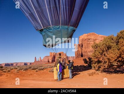 Un ballon à air chaud des terres dans la Monument Valley Navajo Tribal Park en Arizona. Dans l'arrière-plan est la formation rocheuse appelée les Trois Soeurs à fa Banque D'Images