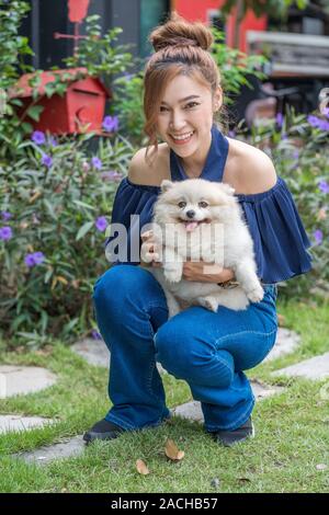 Hug Femme avec chien pomeranian dans le jardin Banque D'Images