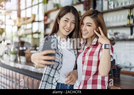 Deux cheerful woman en tenant sur un smartphone selfies Banque D'Images