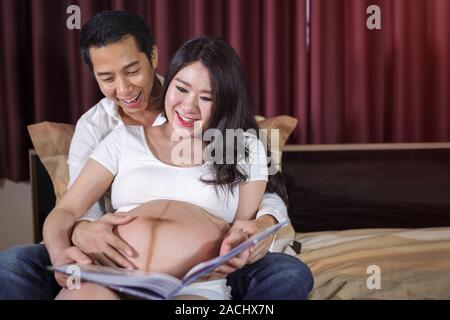 Heureux femme enceinte et son mari à la échographie album photo sur le lit Banque D'Images