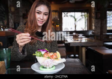 Woman eating Sashimi au saumon Salade épicée au restaurant Banque D'Images