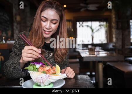 Woman eating Sashimi au saumon Salade épicée au restaurant Banque D'Images