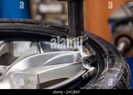 Montage des pneus de roues de voiture sur équipement spécial au cours de la dépose d'un pneumatique à partir d'un disque par un crochet avant l'hiver après l'été et vice versa. Banque D'Images