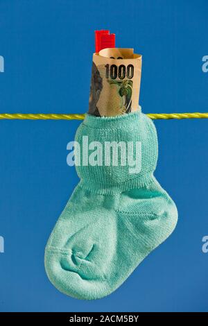 Chaussettes bébé sur corde avec billets de yen Banque D'Images