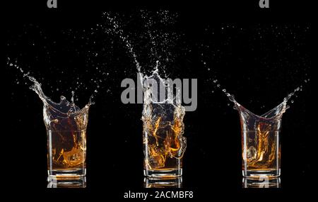 Verres de whisky avec splash, isolé sur fond noir Banque D'Images