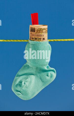 Chaussettes bébé sur corde avec billets de yen Banque D'Images