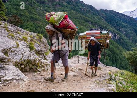 Porteurs transportant de lourdes charges d'un chemin escarpé, les marchandises seront en vente au marché hebdomadaire de la ville Banque D'Images